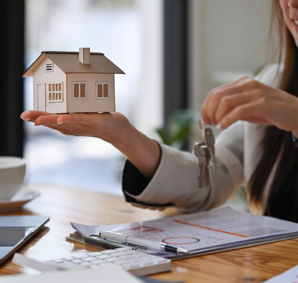 estate agent holding house model and house key in hand. mortgage
