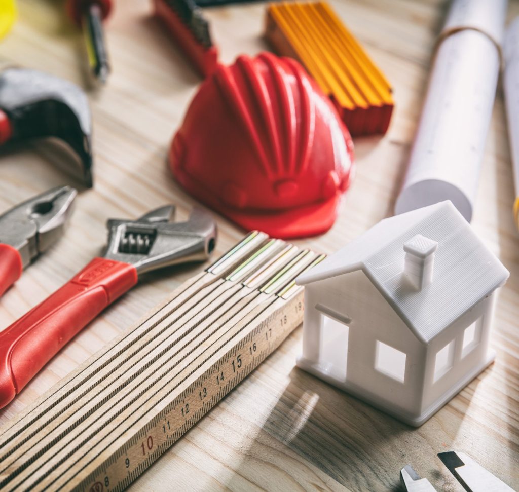 tools, hardhats and project plans on wooden desk